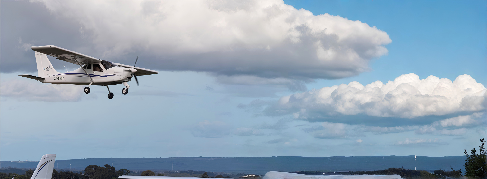 Small airplane flying against a blue sky with white clouds