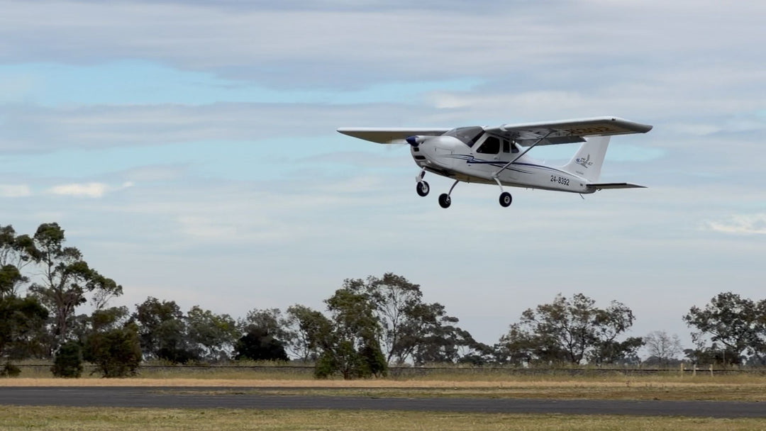 Small airplane taking off from a runway with trees in the background