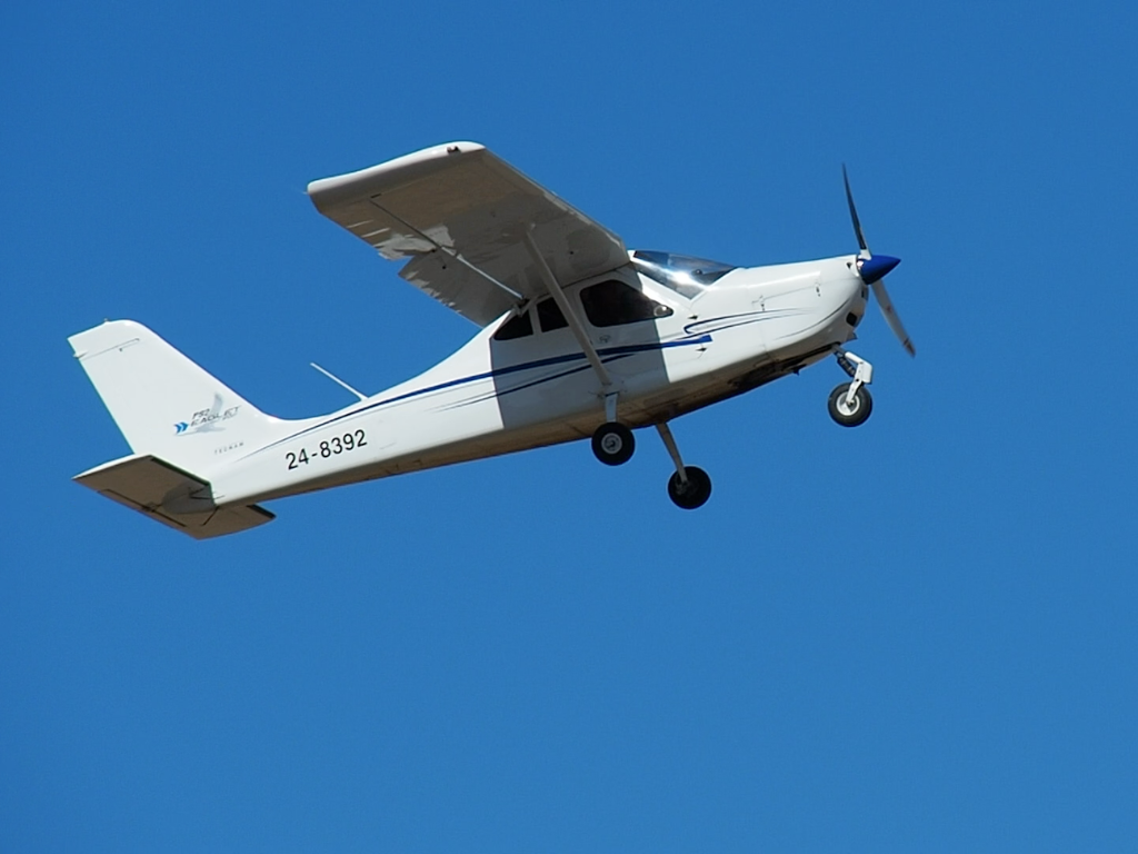 Small airplane flying against a clear blue sky